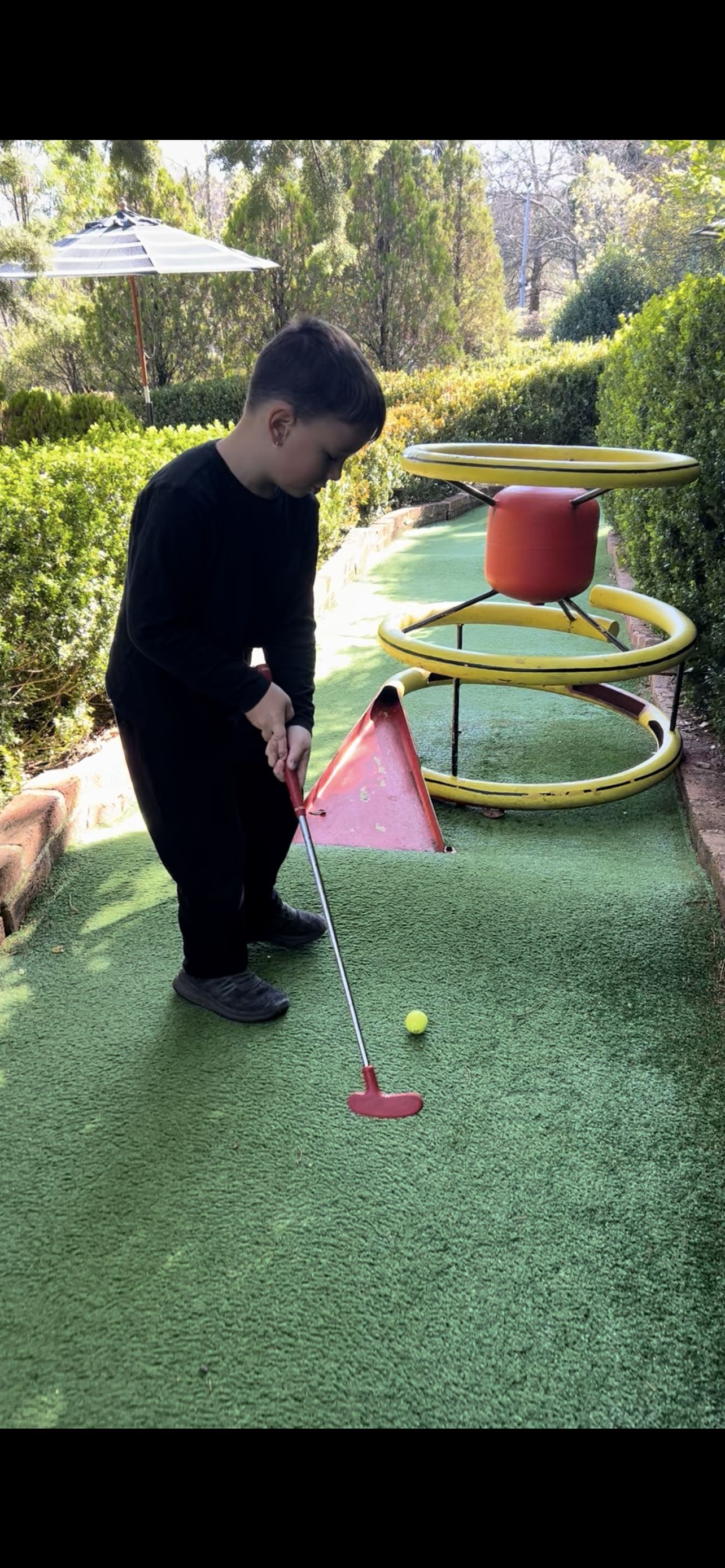 A young person lining up a putt at mini golf